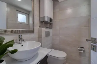 a bathroom with a sink and a toilet and a mirror at Bungalow Lux in Novi Banovci
