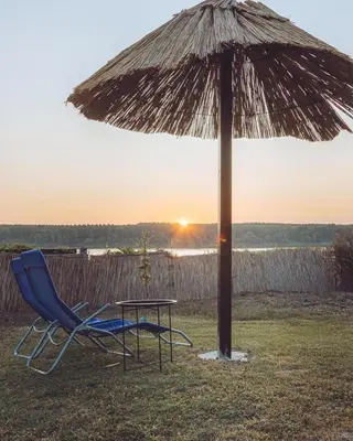 a chair and a table under an umbrella at Bungalow Lux in Novi Banovci