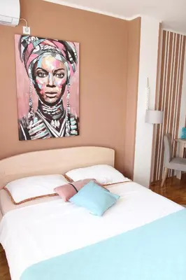 a bedroom with a bed with a painting on the wall at Apartmani Elixir in Nova Pazova