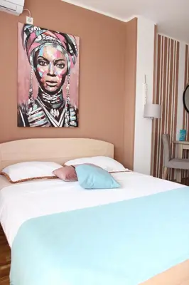 a bedroom with a bed with a painting on the wall at Apartmani Elixir in Nova Pazova