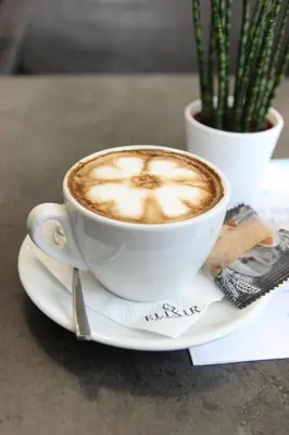 a cup of coffee on a plate on a table at Apartmani Elixir in Nova Pazova