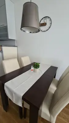 a dining room table and chairs with a clock on the wall at West 65 apartment in Belgrade