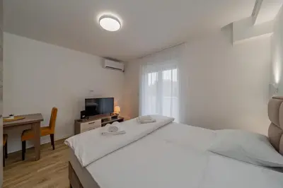 a white bedroom with a large bed and a desk at M Apartments in Belgrade