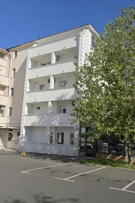 a white apartment building with a tree in front of it at M Apartments in Belgrade