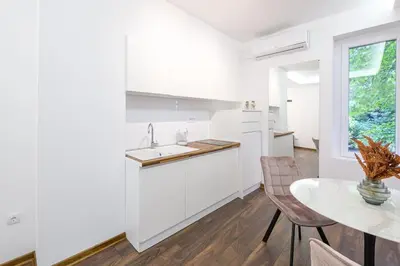 a kitchen with white cabinets and a table and a window at Marshal Dedinje in Belgrade