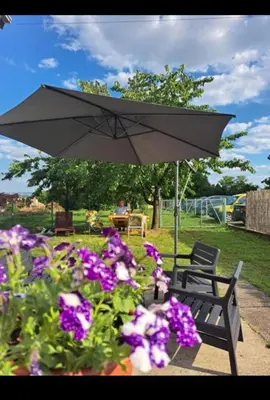 a bench with an umbrella next to some flowers at Happy House in Belgrade