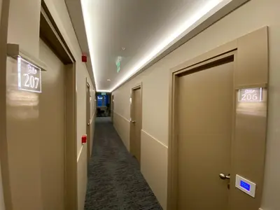 a corridor of a hospital hallway with doors and signs at Konak Stella in Belgrade