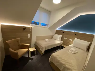 a hotel room with two beds and a chair at Konak Stella in Belgrade