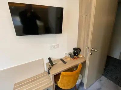 a television on a wall above a table with a yellow chair at Konak Stella in Belgrade