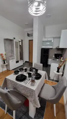 a living room with a table and chairs and a kitchen at Alek Place in Novi Beograd
