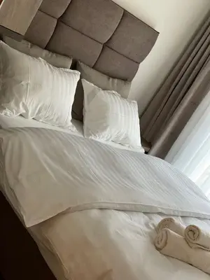 a white bed with white pillows and a stuffed animal on it at Perla Lux apartmani in Inđija