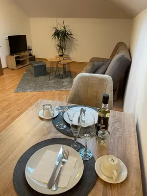 a table with plates and wine glasses on it in a living room at Despot apartmani in Mladenovac