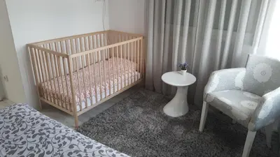 a crib and a chair in a room at Apartment Div 1 in Dušanovac (historical)