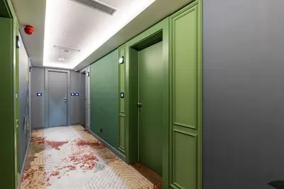 a corridor with green doors and a red floor at Calisi Hotel in Belgrade