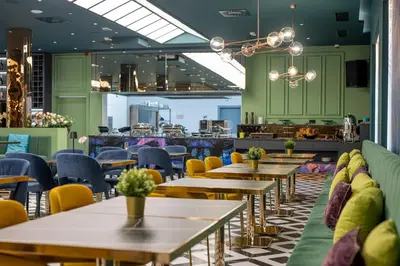 a row of tables and chairs in a restaurant with green walls at Calisi Hotel in Belgrade