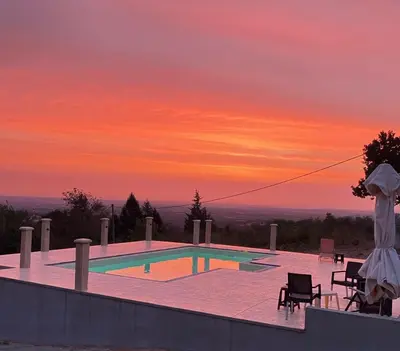 a swimming pool with a sunset in the background at Imanje POGLED in Arandjelovac