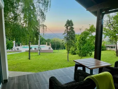 a patio with a table and chairs and a yard at Imanje POGLED in Arandjelovac