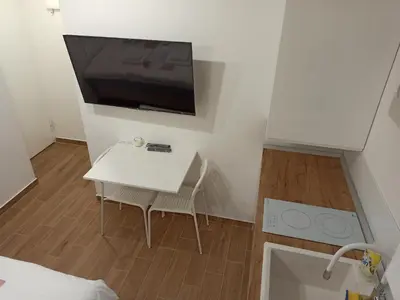 a small room with a white table and a tv on the wall at Milash in Karaburma