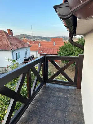 a balcony with a wooden fence and a view of roofs at Apartman Dunja in Arandjelovac