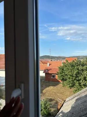 a hand is looking out a window at a building at Apartman Dunja in Arandjelovac