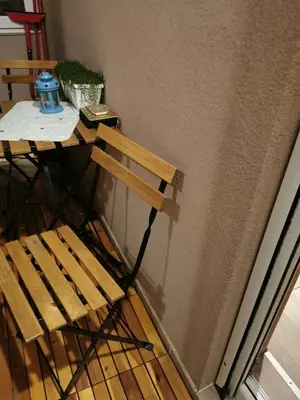 a wooden chair sitting next to a table next to a wall at Lux apartman Lena in Belgrade