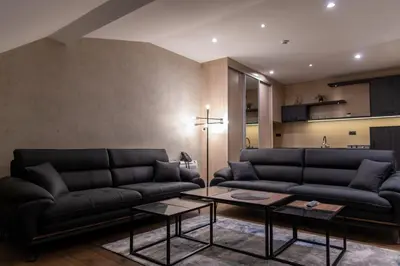 a living room with two black couches and a table at Apart Hotel Maksimum in Belgrade