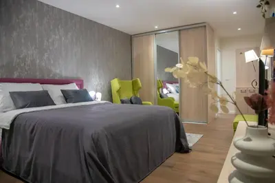 a bedroom with a large bed and green chairs at Apart Hotel Maksimum in Belgrade