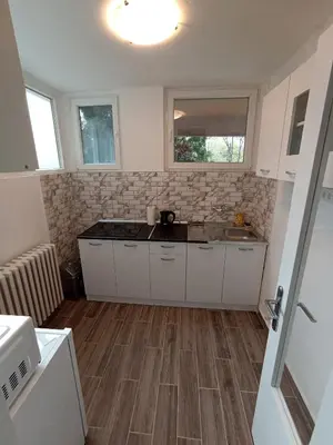 a kitchen with white cabinets and a sink and windows at Apartment Fiesta in Novi Beograd