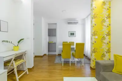 a living room with a table and yellow chairs at Delta Residence Belville in Belgrade