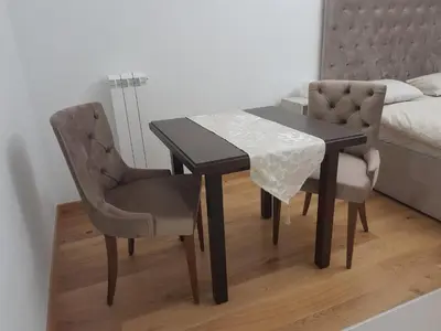 a dining room table and two chairs and a bed at Apartman Marija in Voždovac