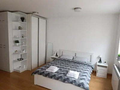 a white bedroom with a bed and white shelves at WHITE apartment in Belgrade