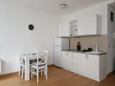 a kitchen with white cabinets and a table and chairs at WHITE apartment in Belgrade
