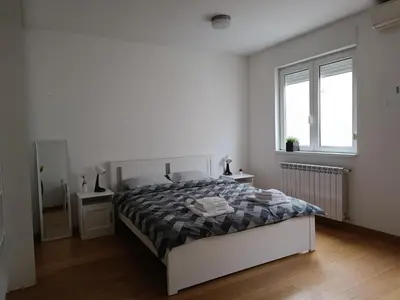 a white bedroom with a bed and two windows at WHITE apartment in Belgrade
