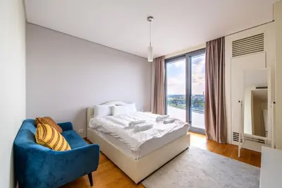 a bedroom with a bed and a blue chair at BW Residences penthouse 2BDR with pool&gym in Belgrade