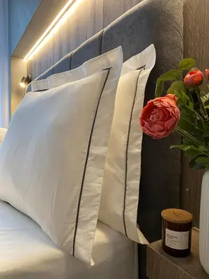 two white pillows sitting on a bed with a rose at DOM Boutique Apartments AURORA in Belgrade