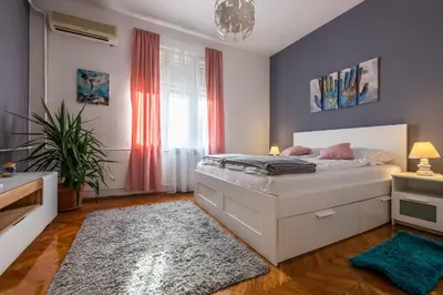 a bedroom with a white bed and a rug at Neimar Apartment with Great Wi-Fi and free parking in Belgrade