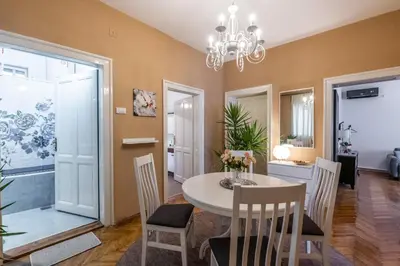 a dining room with a table and chairs and a chandelier at Neimar Apartment with Great Wi-Fi and free parking in Belgrade
