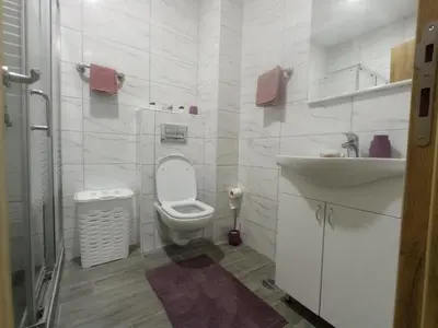 a white bathroom with a toilet and a sink at Apartman Ledine in Ledine