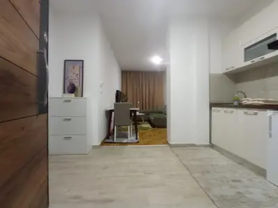 a kitchen with white cabinets and a dining room at Apartman Ledine in Ledine