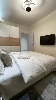 a bedroom with a large white bed with a flat screen tv at Filip Luxury Suite in Belgrade