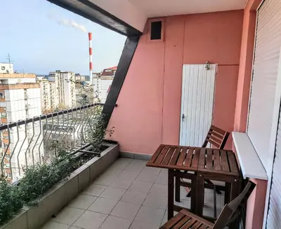 a balcony with two wooden chairs and a pink wall at Peti in Belgrade
