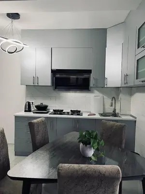 a kitchen with a table and chairs and a kitchen with white cabinets at \u99a8\u4e4b\u5bb6-\u534e\u4eba\u516c\u5bd3\u6c11\u5bbf \u4e09\u5ba4\u4e00\u5385 in Ledine