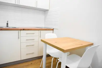 a kitchen with a wooden table and white chairs at Premium Suites Terazije in Belgrade