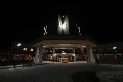 a building with a clock on the top of it at night at Hotel Tamiš & Spa in Pančevo