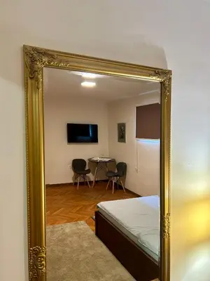 a mirror reflecting a room with a bed and a table at Dorcoleta Apartment in Belgrade