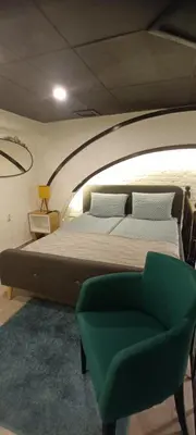 a bedroom with a large bed and a green chair at Old Café Spa Apartment - Unique space in Belgrade
