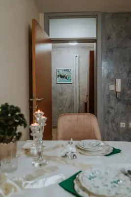 a dining room table with a white table cloth and plates at Apartman David in Ruma