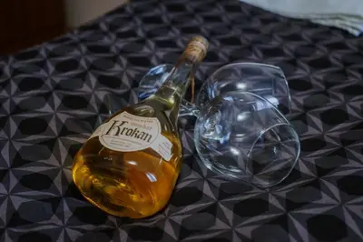 a bottle of alcohol next to two glasses on a table at Apartman David in Ruma
