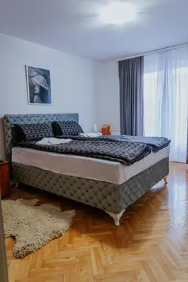 a large bed in a room with a wooden floor at Apartman David in Ruma