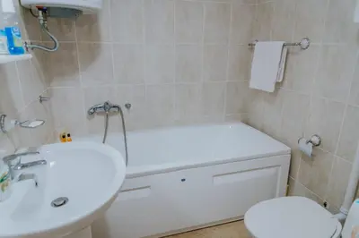 a bathroom with a white tub and a toilet and a sink at Apartman David in Ruma